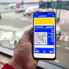 Smartfon z kartą pokładową Ryanair, pokazujący jak pobrać karty pokładowe Ryanair. Widok na lotnisko.
