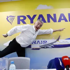 Michael O'Leary, znany jako właściciel Ryanaira, wesoło pozuje na tle samolotu i logo linii lotniczych.