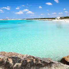 Turkusowe morze i biała plaża na Palma de Mallorca. Słoneczny dzień, błękitne niebo z chmurkami.