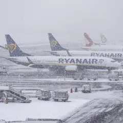 Samoloty Ryanair i Lauda stoją na lotnisku podczas zamieci. Sprawdź, jak sprawdzić powód opóźnienia lotu w takich warunkach.