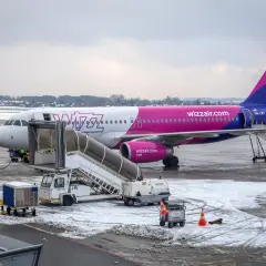 Samolot Wizz Air na lotnisku zimą, z drabiną i sprzętem naziemnym.