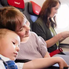 Dzieci śpią i siedzą obok mamy w samolocie. Dowiedz się, jak dodać dziecko do rezerwacji Ryanair.