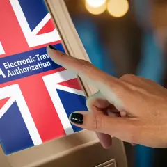 Palec dotyka ekranu z flagą Wielkiej Brytanii i napisem ETA. Czy do Londynu trzeba mieć wizę? ETA to elektroniczne zezwolenie na podróż.