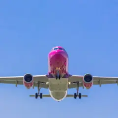 Różowy samolot Wizzair z wysuniętym podwoziem, gotowy do lądowania. Tak wygląda odprawa online Wizzair - szybko i sprawnie!