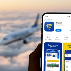 Telefon z aplikacją Ryanair na tle samolotu. Dowiedz się, jak wydrukować kartę pokładową z aplikacji Ryanair, by podróżować bez stresu.