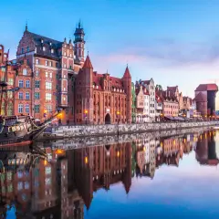 Zachód słońca nad Motławą w Gdańsku, z zabytkowymi kamieniczkami i żaglowcem. Idealne miejsce na podróż, gdy planujesz loty Wrocław Gdańsk.