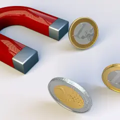Czerwony magnes podkowowy przyciąga monety euro.
