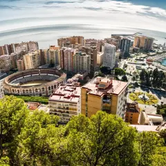 Widok na Malagę z lotu ptaka: arena, port, morze i budynki. Idealne miejsce na wakacje, warto zaplanować loty do Malagi.