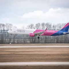 Samolot Wizz Air z wysuniętym podwoziem ląduje na pasie startowym.