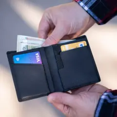 Ręce wkładają pieniądze i karty do czarnego portfela. Zastanawiasz się, ile euro można przewieźć w samolocie?