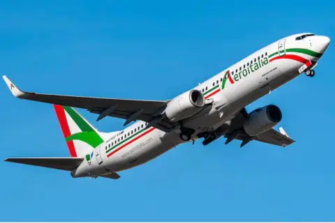 Samolot Aeroitalia z zielono-biało-czerwonym malowaniem wznosi się na tle błękitnego nieba. Idealny na loty Lublin Rzym.