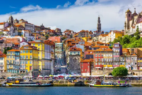 Kolorowe kamienice Porto nad rzeką, z widokiem na wieżę i kościoły. Marzenie o lotach z Gdańska do Porto.
