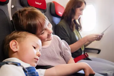 Dzieci śpią i siedzą obok mamy w samolocie. Dowiedz się, jak dodać dziecko do rezerwacji Ryanair.