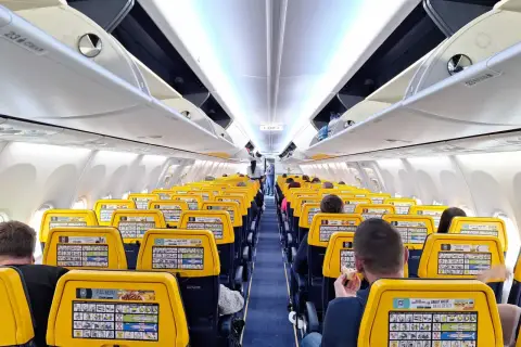 Wnętrze samolotu Ryanair z żółtymi zagłówkami. Na jednym z nich widoczna jest reklama "Great Value Meal Deals", która może pomóc w znalezieniu informacji, jak w aplikacji Ryanair zmienić walutę.