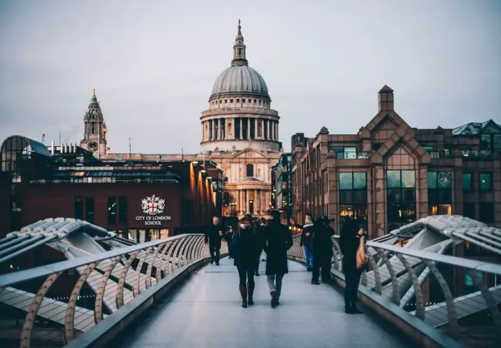 Most ludzi na moście Millennium Bridge w Londynie, z widokiem na katedrę św. Pawła.