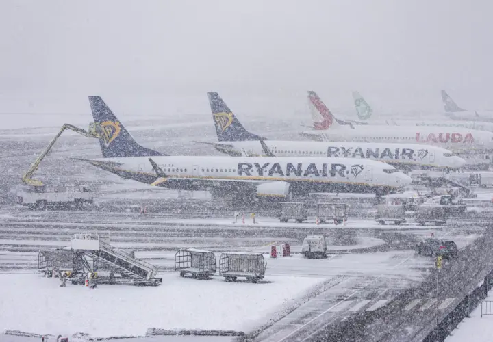 Samoloty Ryanair i Lauda stoją na lotnisku podczas zamieci. Sprawdź, jak sprawdzić powód opóźnienia lotu w takich warunkach.