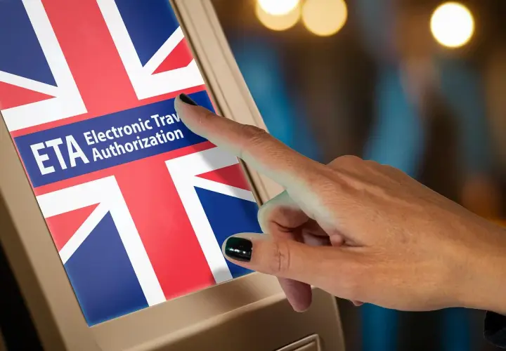 Palec dotyka ekranu z flagą Wielkiej Brytanii i napisem ETA. Czy do Londynu trzeba mieć wizę? ETA to elektroniczne zezwolenie na podróż.