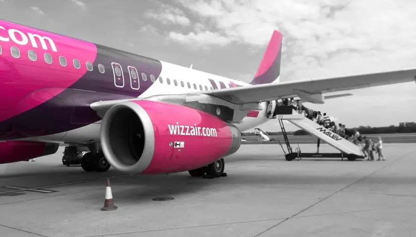 Samolot Wizzair na płycie lotniska. Pasażerowie wsiadają po schodkach. Zastanawiasz się, jak odwołać lot Wizzair?