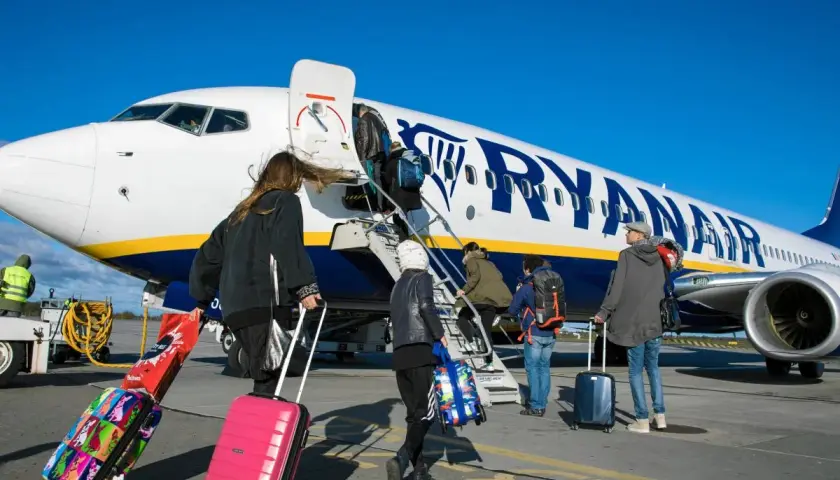 Odprawa Ryanair: pasażerowie z walizkami wchodzą po schodkach do samolotu.
