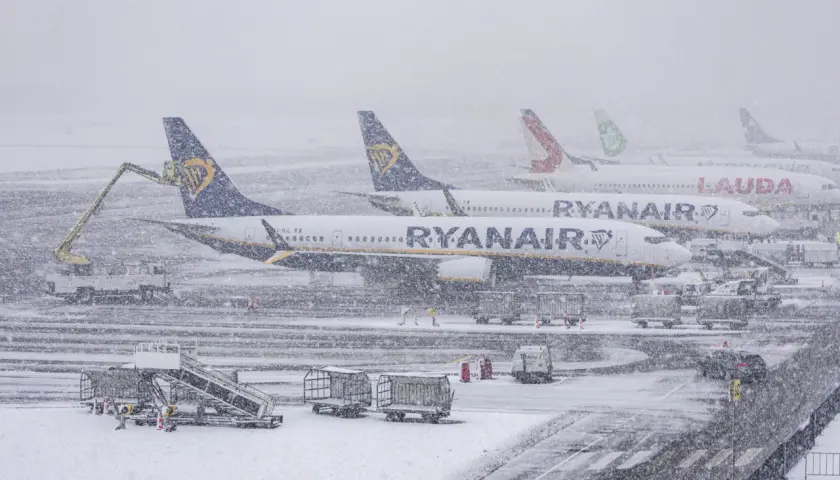Samoloty Ryanair i Lauda stoją na lotnisku podczas zamieci. Sprawdź, jak sprawdzić powód opóźnienia lotu w takich warunkach.