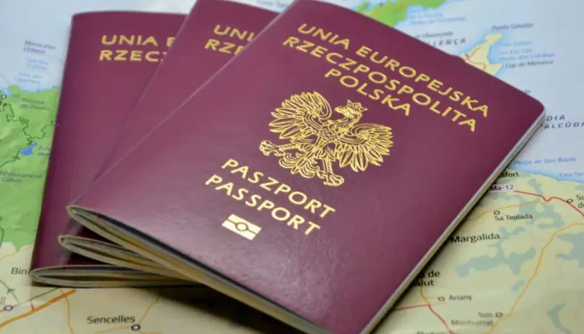 Trzy polskie paszporty leżą na mapie. Zastanawiasz się, ile trwa wyrobienie paszportu?