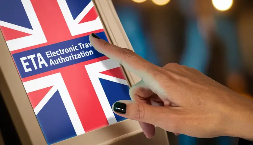 Palec dotyka ekranu z flagą Wielkiej Brytanii i napisem ETA. Czy do Londynu trzeba mieć wizę? ETA to elektroniczne zezwolenie na podróż.