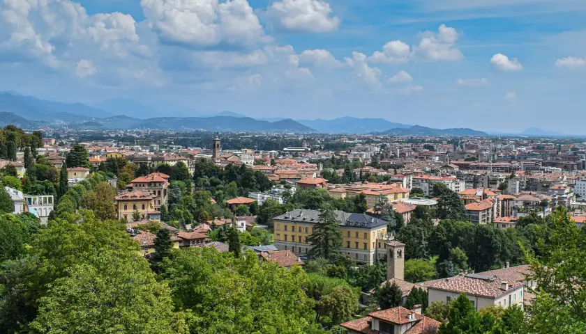 Widok na Bergamo z licznymi dachami i zielenią, idealne miejsce na loty do Bergamo.
