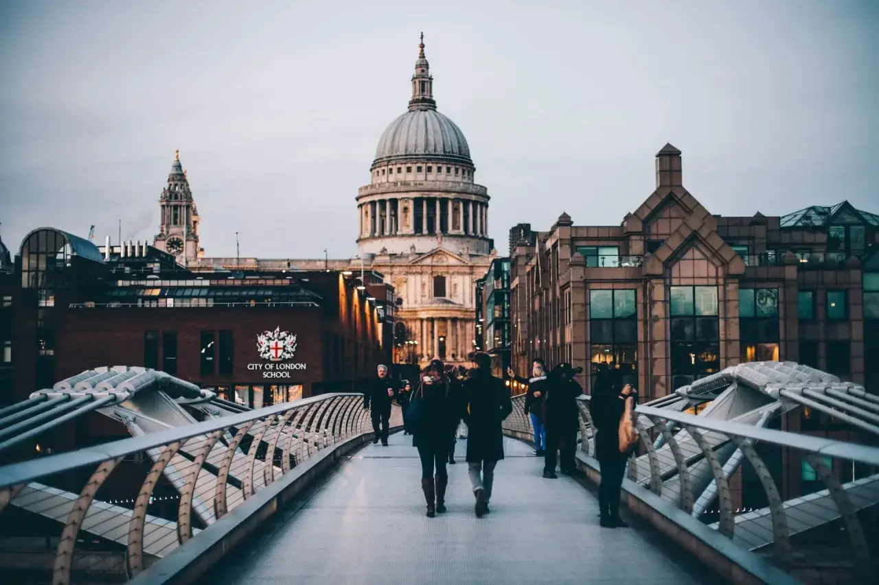 Most ludzi na moście Millennium Bridge w Londynie, z widokiem na katedrę św. Pawła.