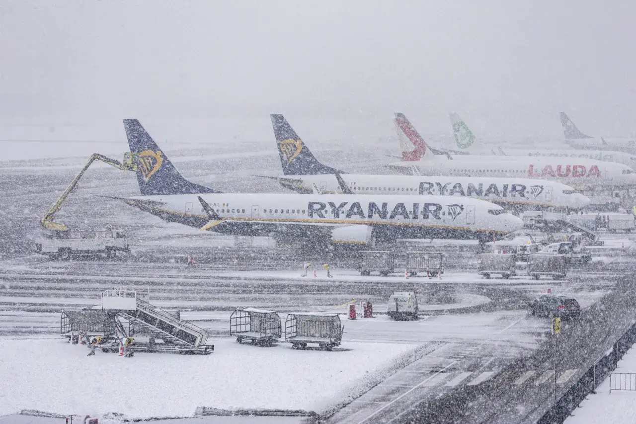 Samoloty Ryanair i Lauda stoją na lotnisku podczas zamieci. Sprawdź, jak sprawdzić powód opóźnienia lotu w takich warunkach.