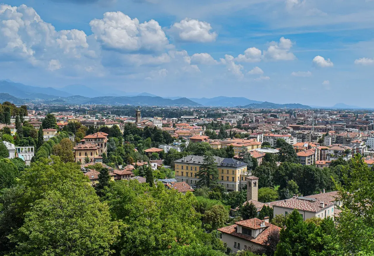 Widok na Bergamo z licznymi dachami i zielenią, idealne miejsce na loty do Bergamo.