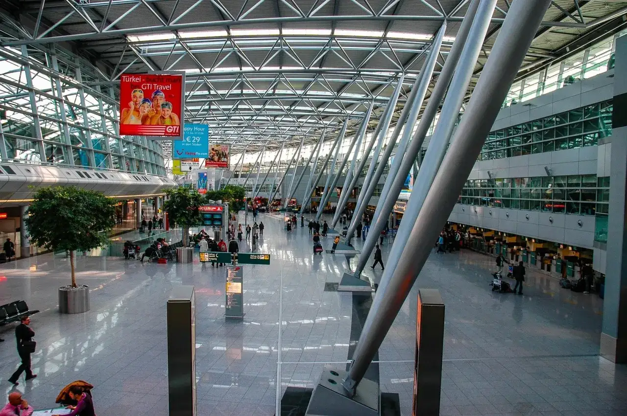 Nowoczesny terminal lotniska z ludźmi i reklamami. Zastanawiasz się, ile wczesniej być na lotnisku?