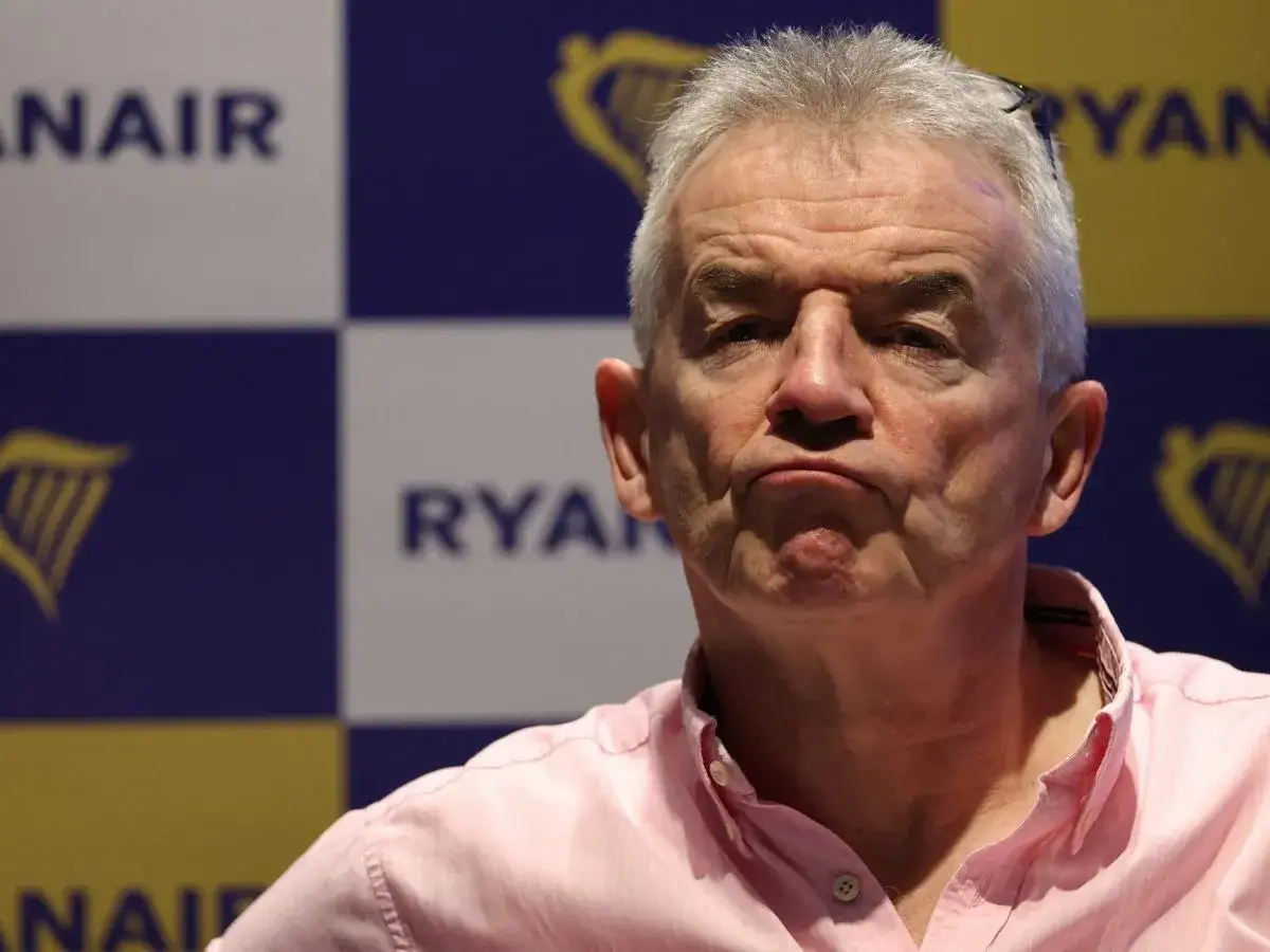 Michael O'Leary, znany jako właściciel Ryanaira, w różowej koszuli na tle logo linii lotniczych.