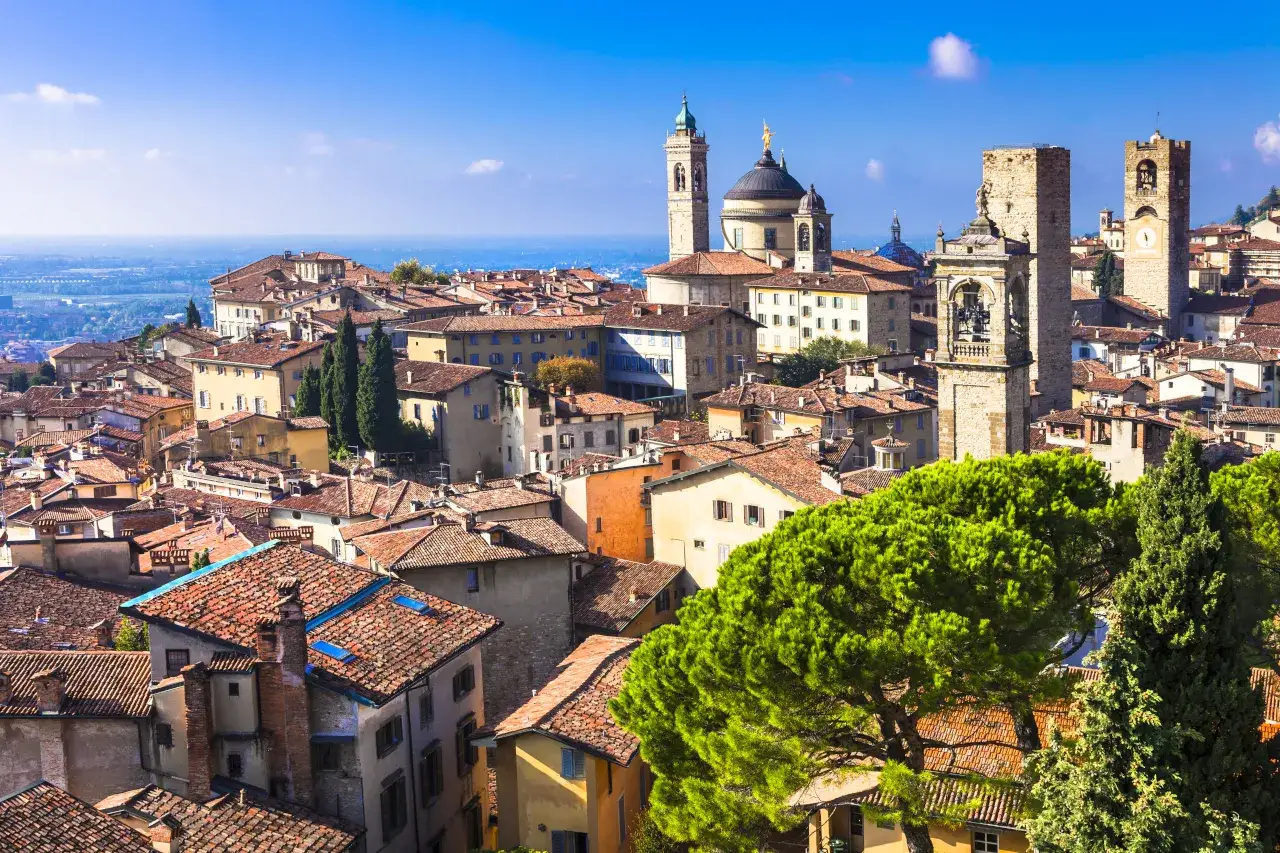 Widok na zabytkowe miasto z wieżami i kopułą, idealne miejsce na loty do Bergamo.