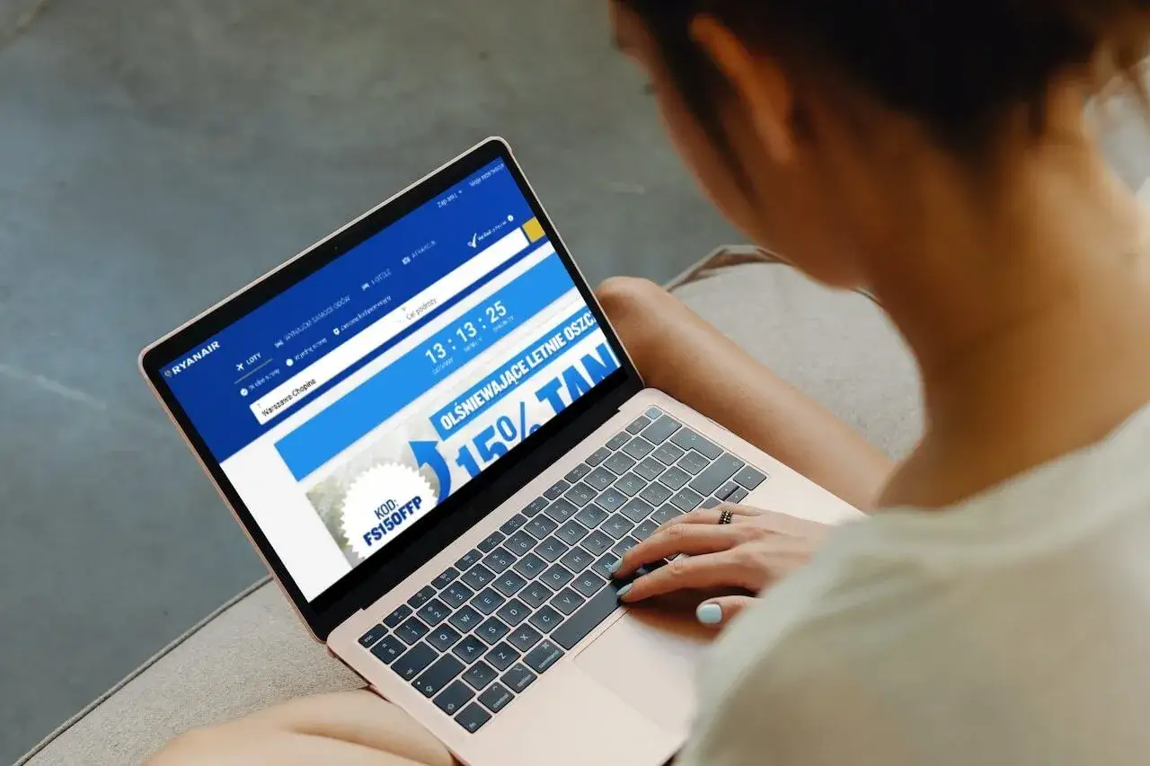 Kobieta szuka informacji, jak w aplikacji Ryanair zmienić walutę, przeglądając ofertę lotów na laptopie.