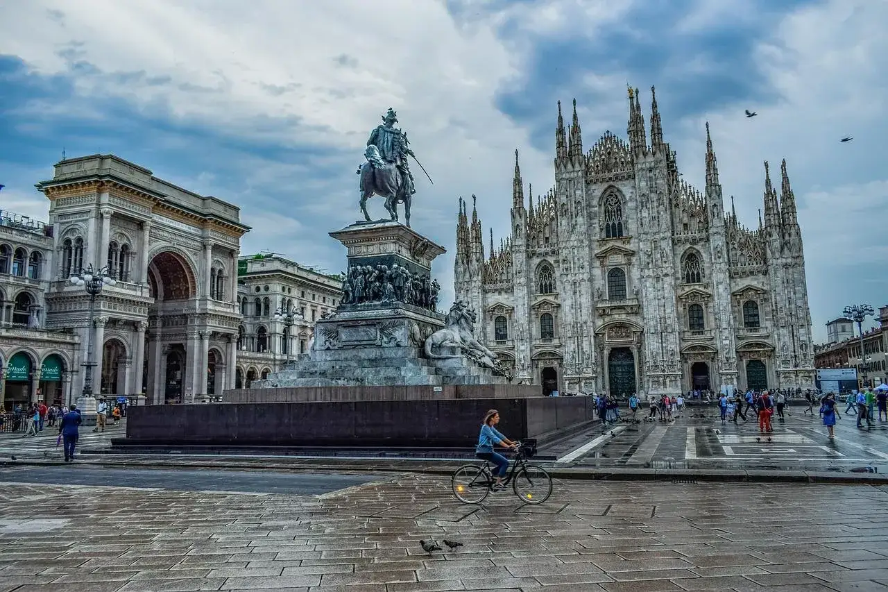Kobieta na rowerze przemierza plac przed Katedrą Duomo w Mediolanie. Idealne miejsce na rozpoczęcie podróży, gdy szukasz loty do Bergamo.