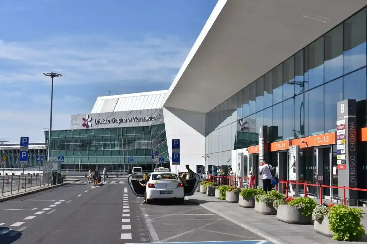 Nowe auto czeka, by jak odebrać pasażera z lotniska Chopina. Widok na nowoczesny terminal i parking.
