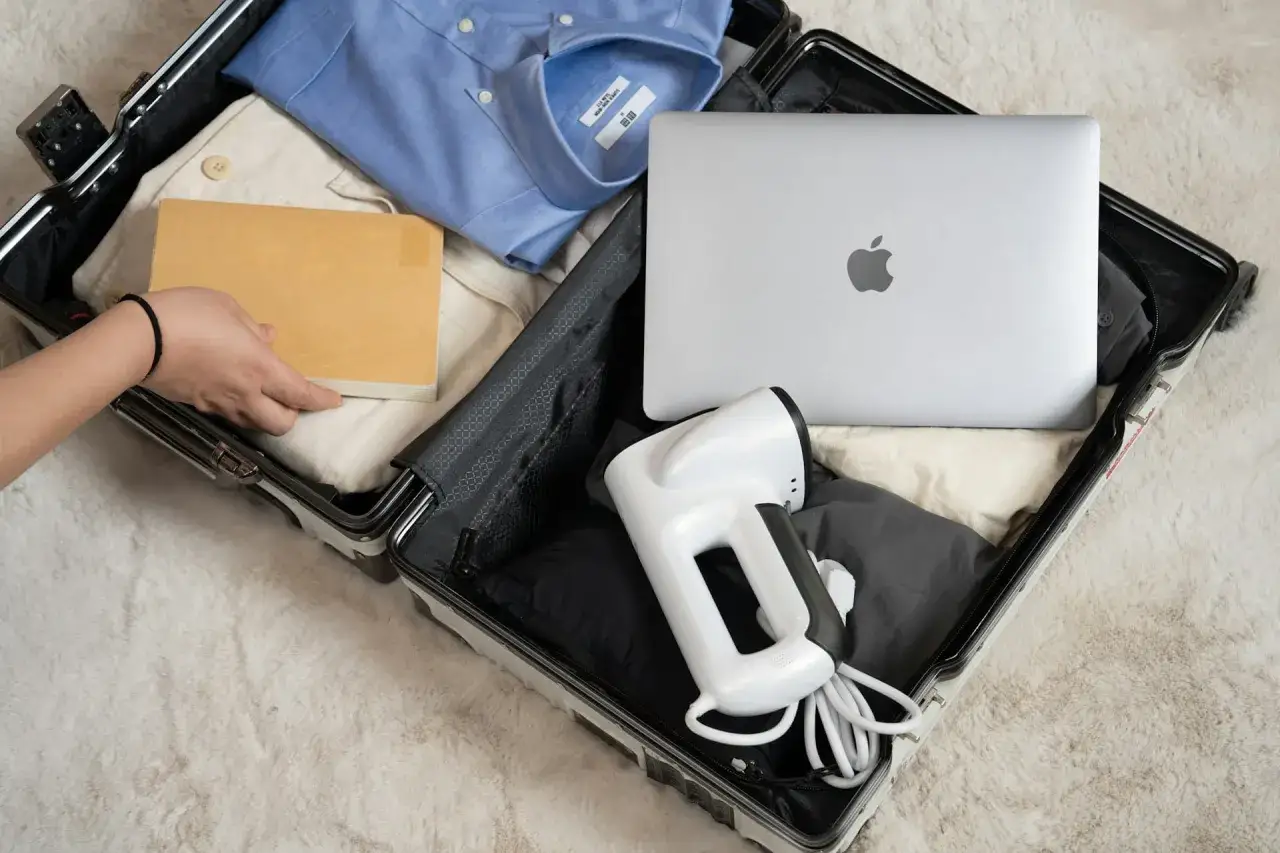 Pakowanie do bagażu rejestrowanego: koszula, spodnie, książka, laptop i podręczne żelazko.