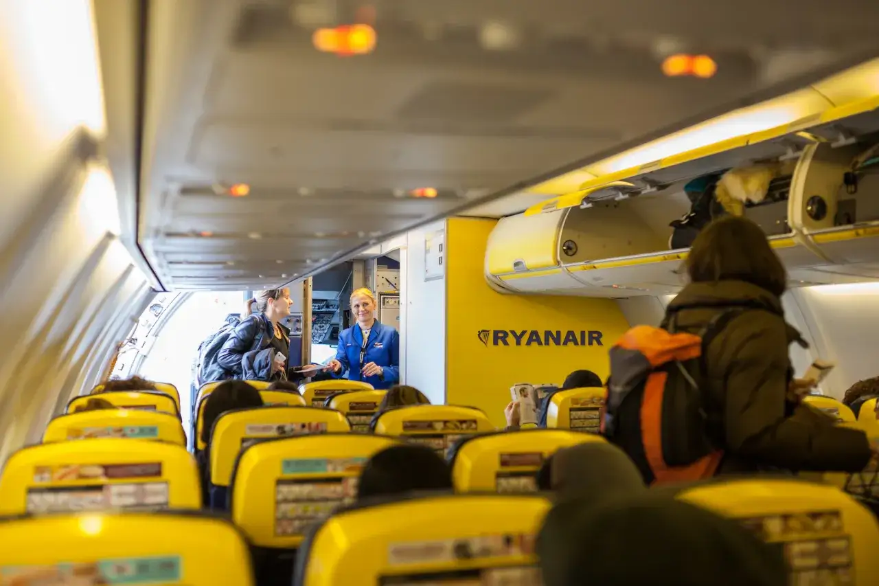 Wnętrze samolotu Ryanair. Stewardessa pomaga pasażerce, która zastanawia się, jak dodać dziecko do rezerwacji Ryanair.