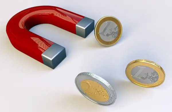 Czerwony magnes podkowowy przyciąga monety euro.